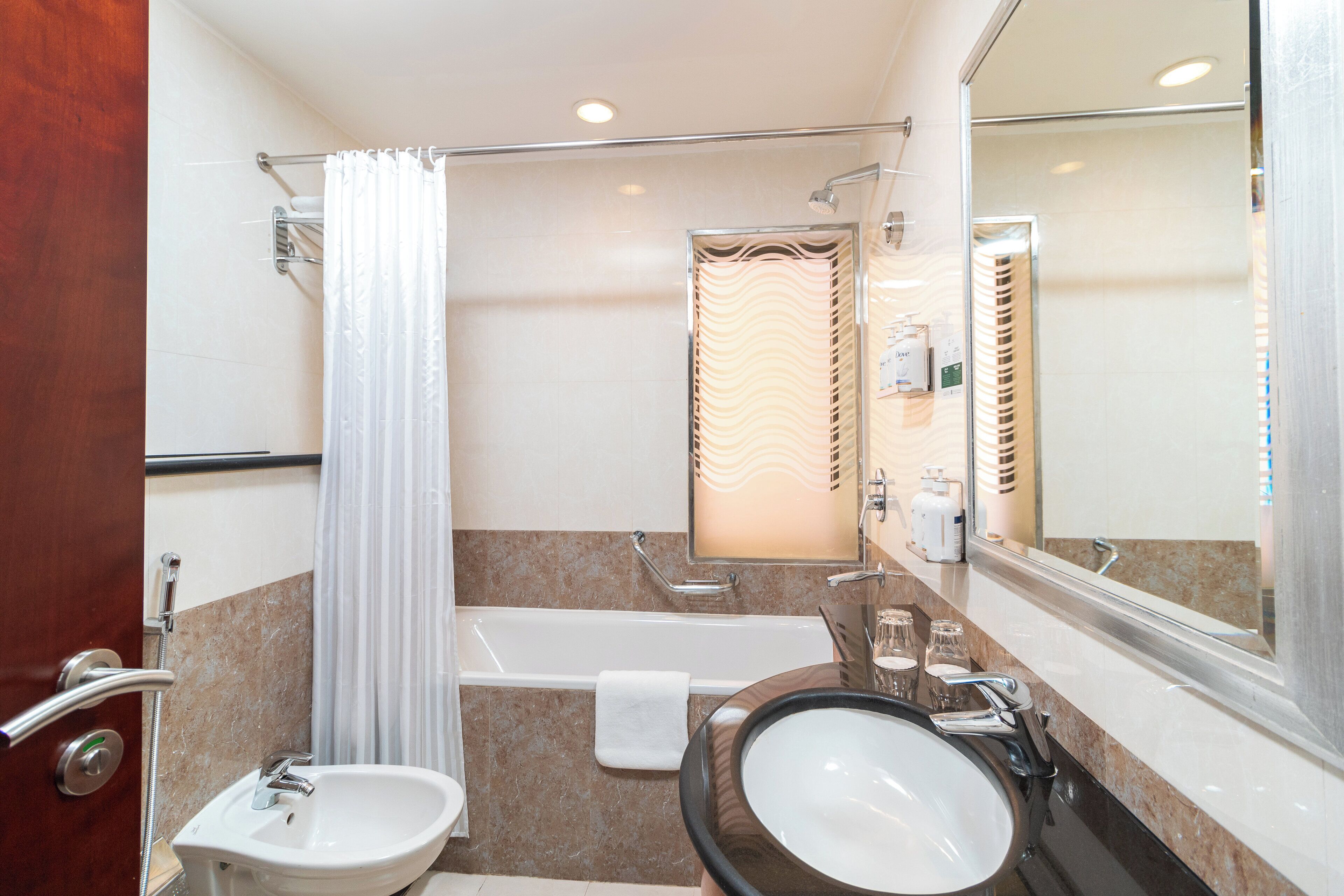Un baño con bañera, lavamanos y espejo.