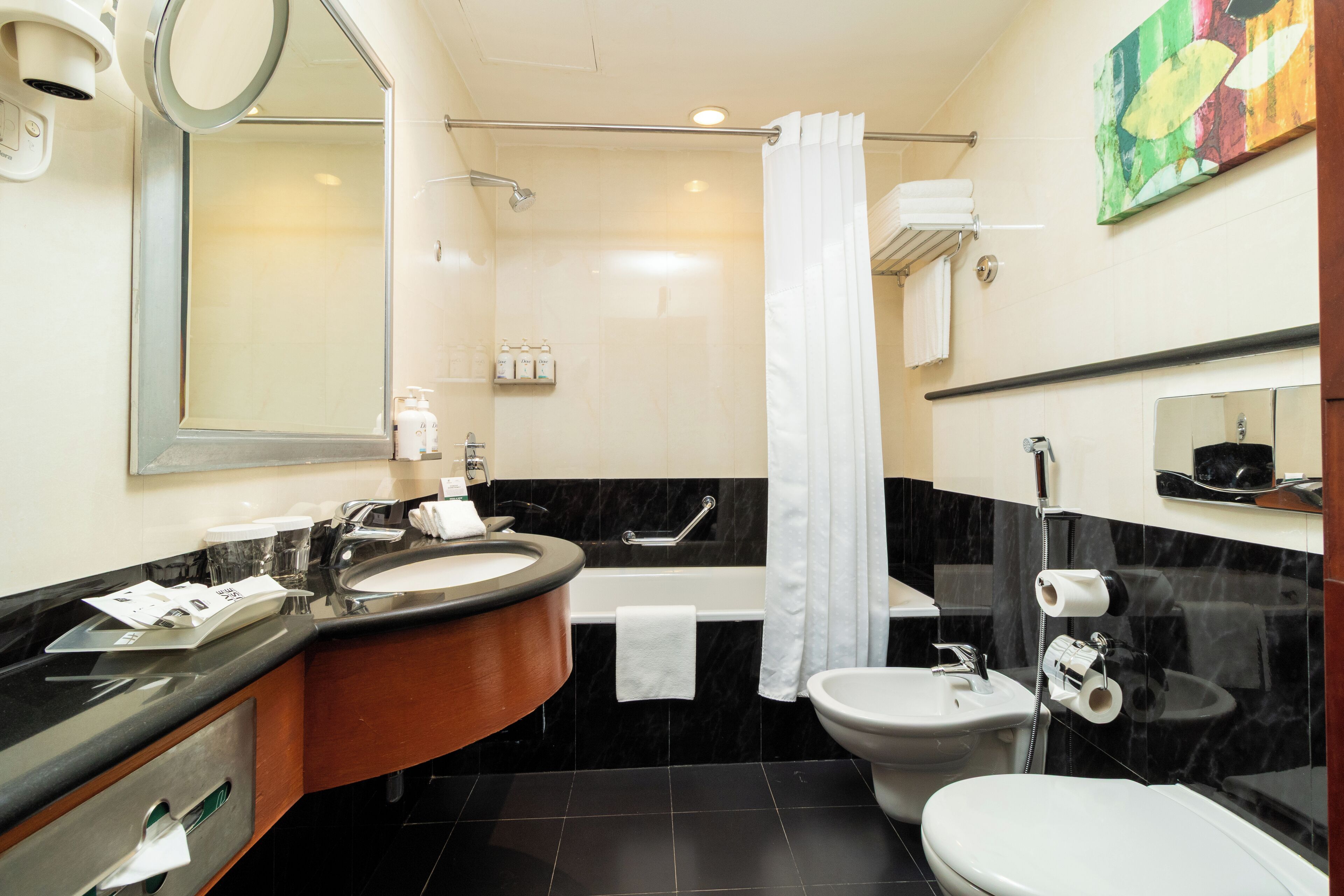 Un baño moderno con un espejo grande, un lavamanos, una bañera, un inodoro y un bidé.