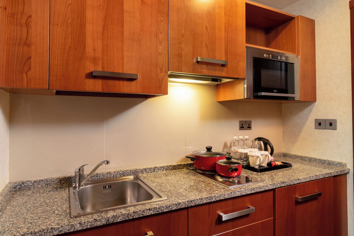 A kitchen with wooden cabinets, a stainless steel sink, a microwave, and a granite countertop.