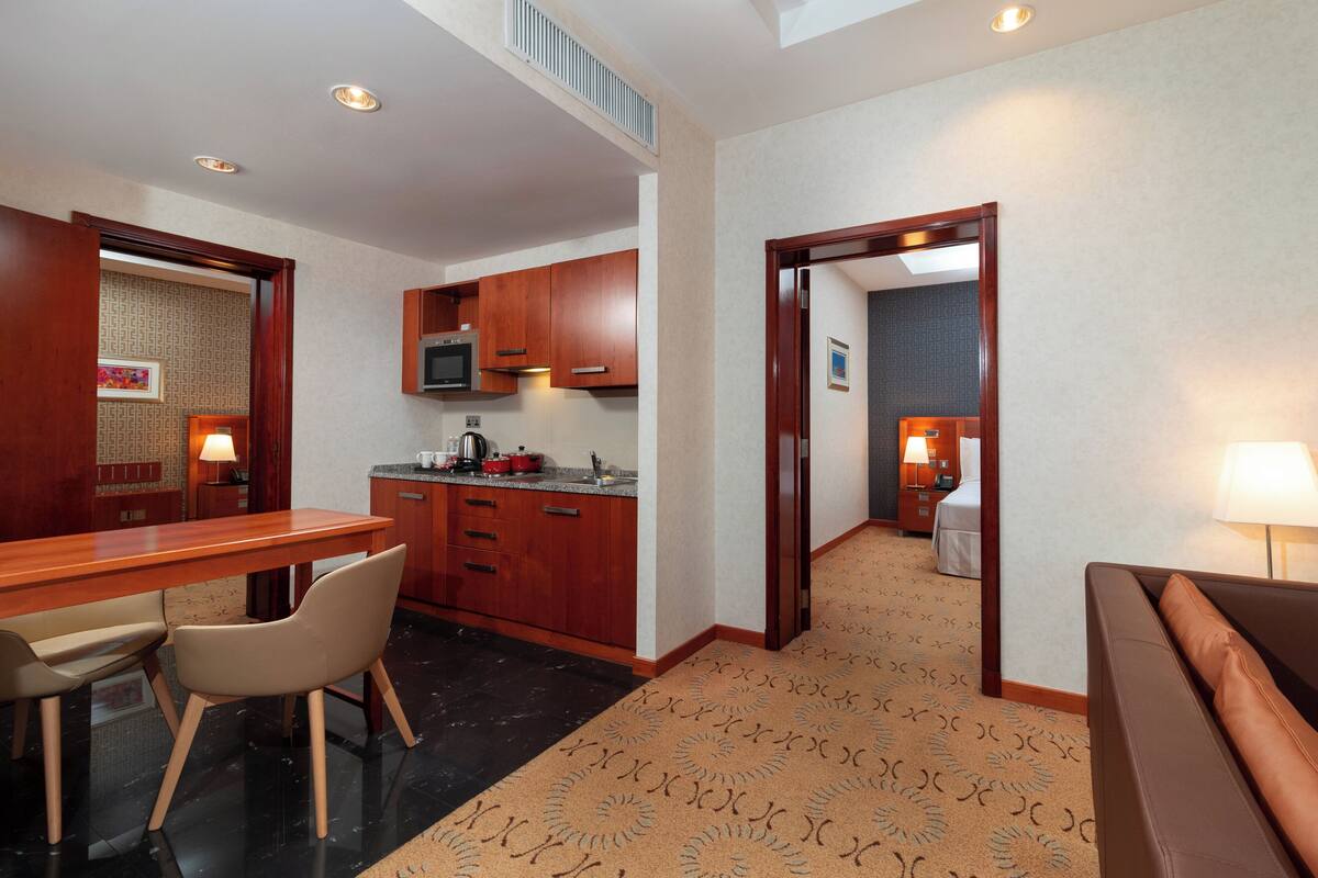 A hotel room with a dining area, kitchenette, and a separate living area.