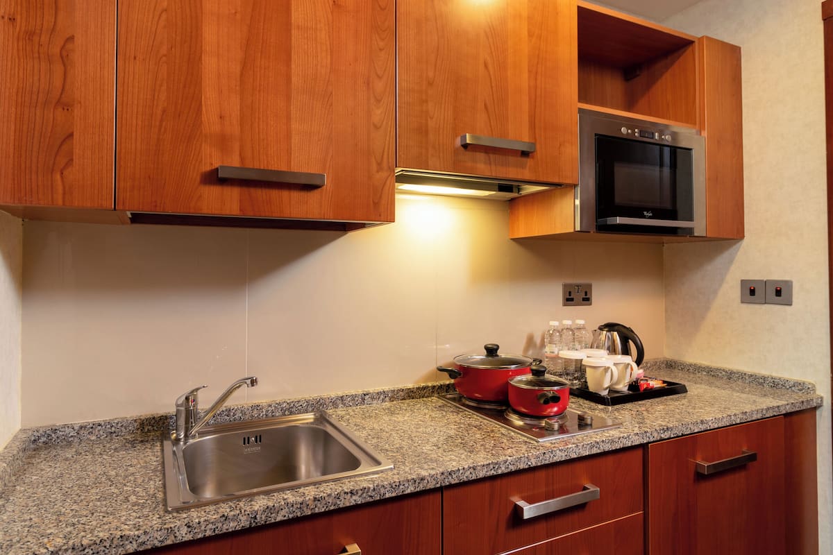 A kitchen with wooden cabinets, a stainless steel sink, a microwave, and a granite countertop.