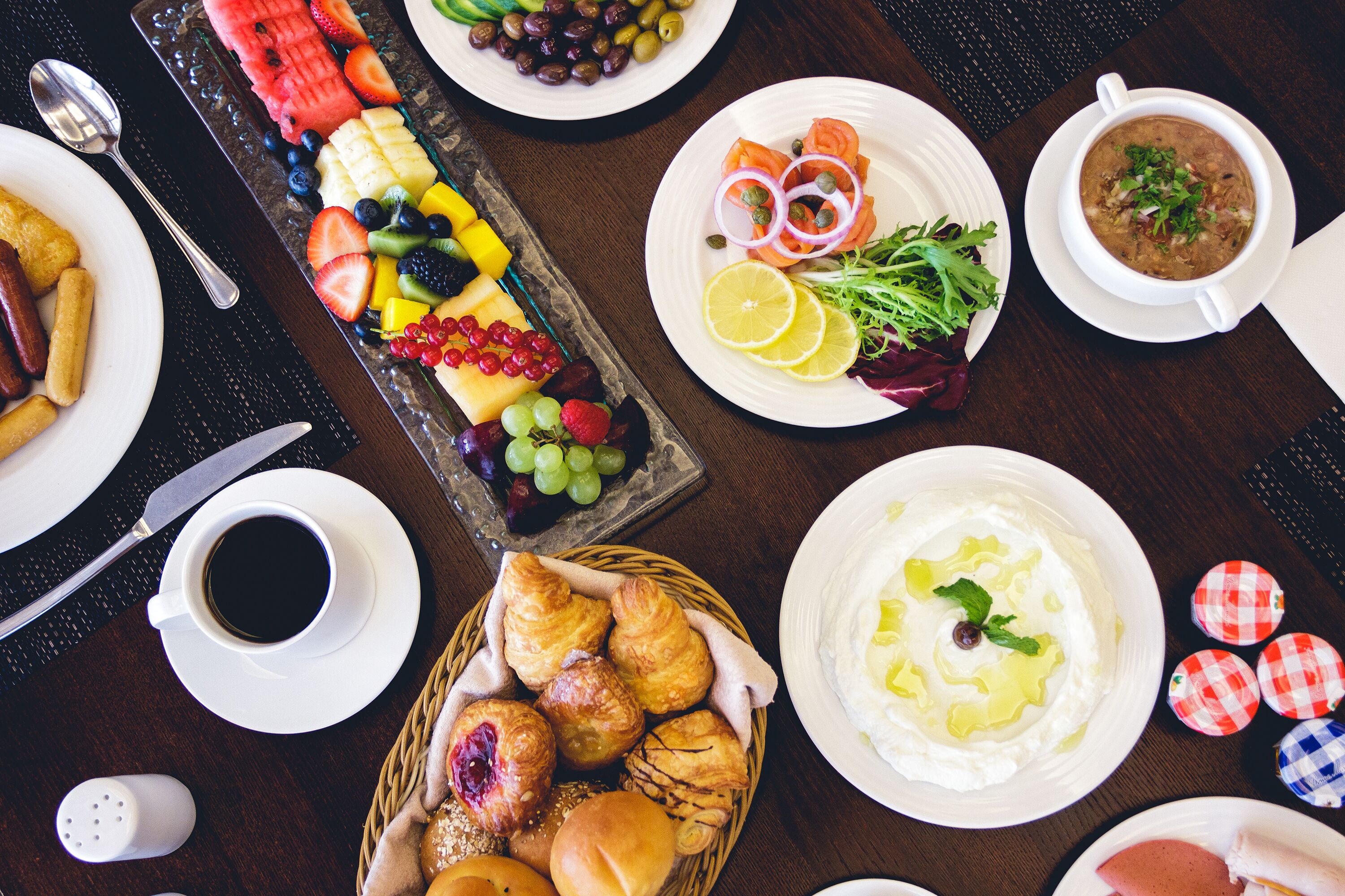 Una variedad de platos, incluyendo una fuente de frutas, sopa y pasteles, sobre una mesa.