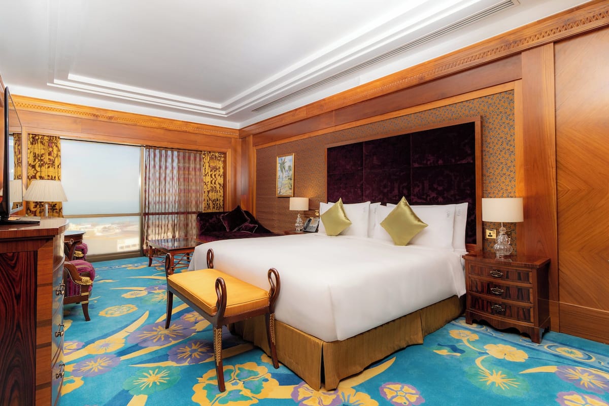 A hotel room with a large bed, a desk, a chair, and a view of the city.