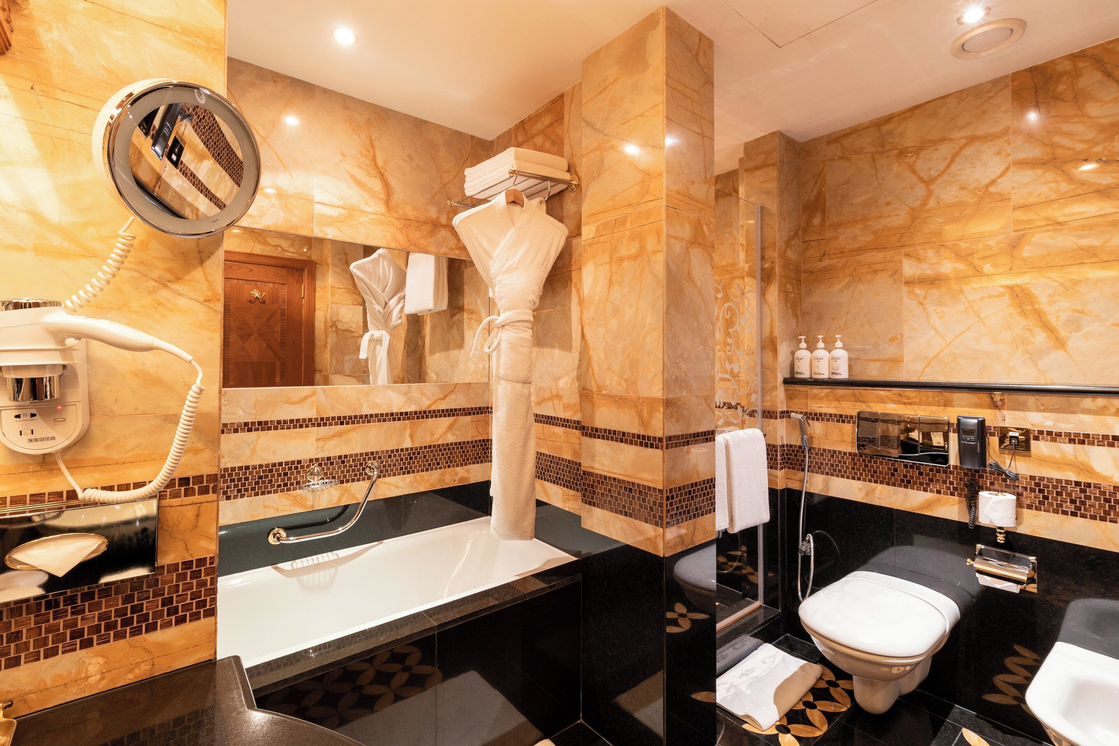 Un baño con pared de mármol, un lavamanos, un inodoro y un secador de pelo.