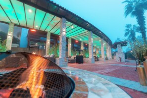 An outdoor patio area with a fire feature, stone pillars, and a covered seating area. - Holiday Inn Suites Kuwait by IHG (Salmiya)