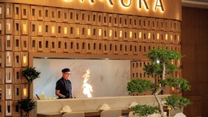 Una recepción con un cartel que dice "SAKURA" y un chef preparando comida.