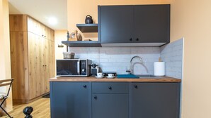 A compact kitchen with dark cabinets, a microwave, a kettle, and a sink. - Savčić Apartmani (Petrovac)