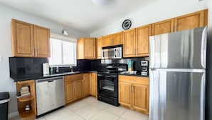 A modern kitchen with wooden cabinets, a stainless steel refrigerator, a microwave, and a dishwasher. - Beautiful Condo Two Blocks to The Beach ! (Cape Canaveral)