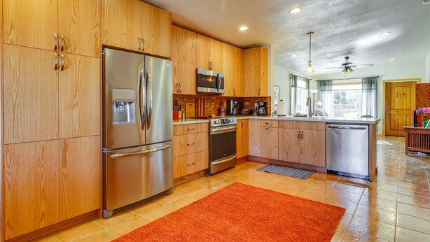 Ett modernt kök med träskåp, rostfria vitvaror och en röd matta.
