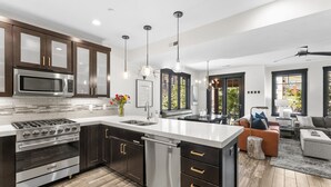 A modern kitchen with dark cabinetry, stainless steel appliances, and a central island. - Experience mountain views at Blackstone Escape, a spacious 3BR townhouse in Park City. (Park City)