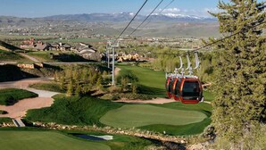 A cable car moving over a golf course with a mountainous backdrop. - Experience mountain views at Blackstone Escape, a spacious 3BR townhouse in Park City. (Park City)