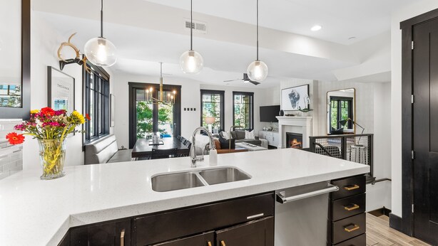 A modern kitchen with a large island, pendant lights, and a vase of flowers. - Experience mountain views at Blackstone Escape, a spacious 3BR townhouse in Park City. (Park City)