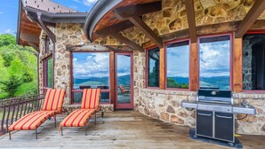 Un espacio al aire libre cubierto con paredes de piedra, amplias ventanas y una estación de parrillada.
