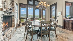 Un comedor con chimenea de piedra, ventanas amplias y una araña.