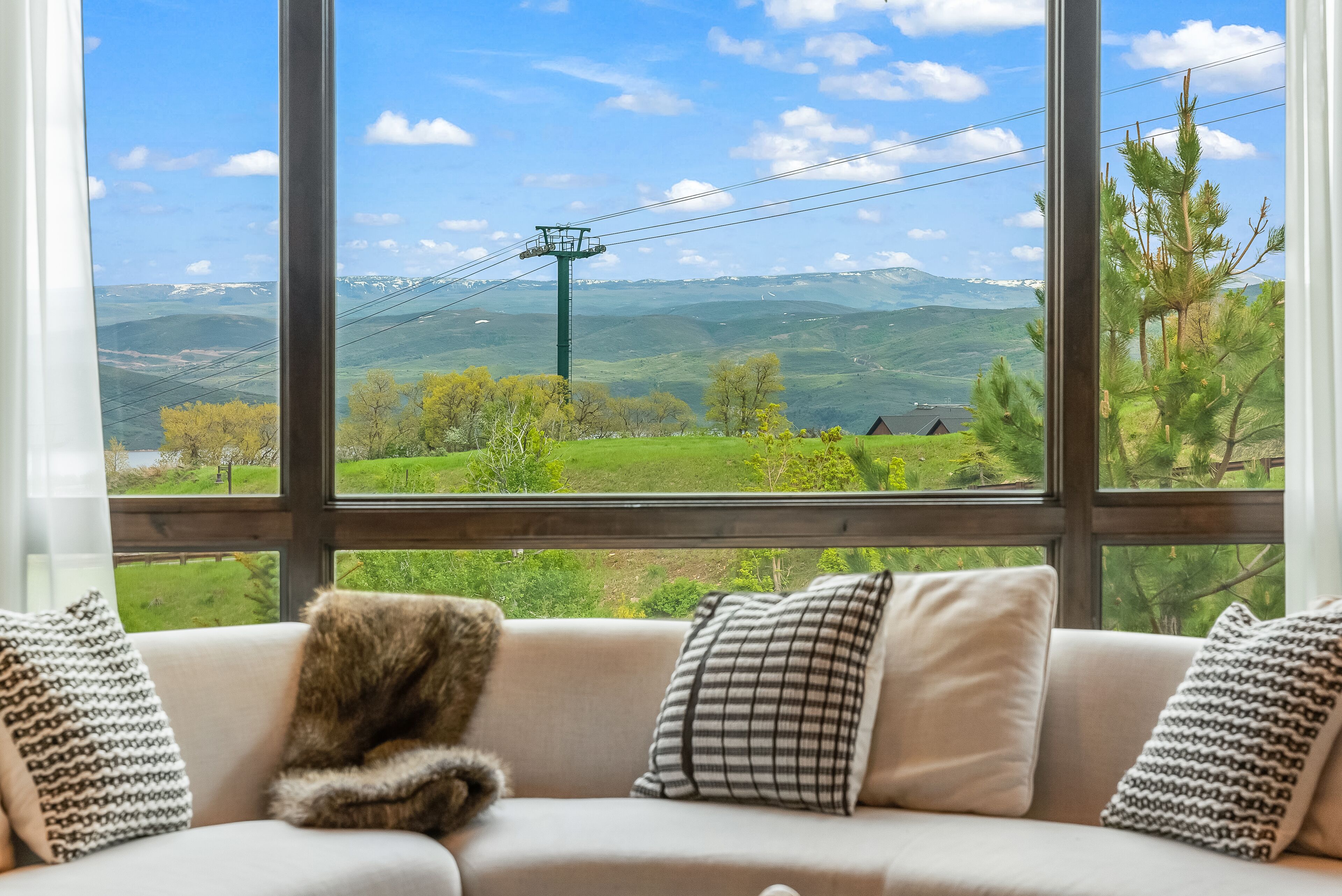 A cozy room with a large window offering a scenic view of rolling hills and a distant mountain range.