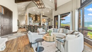 Amplia sala de estar con chimenea, asientos cómodos y ventanas grandes que ofrecen una vista panorámica.