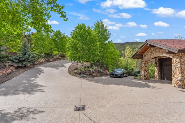 A driveway leading to a stone building with a car parked nearby.