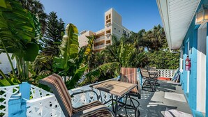An outdoor seating area with a table and chairs, surrounded by a white lattice fence, and tropical plants. - Blue Water Beach Rental #6   A little slice of beach paradise (Indian Rocks Beach)