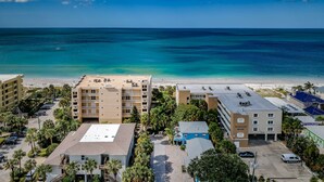 A beachfront hotel with multiple buildings, a parking area, and a view of the ocean. - Blue Water Beach Rental #6   A little slice of beach paradise (Indian Rocks Beach)