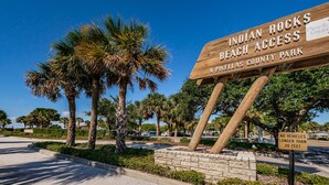 A wooden sign for Indian Rocks Beach Access, a Pinellas County Park, with palm trees and a clear blue sky in the background. - Blue Water Beach Rental #6   A little slice of beach paradise (Indian Rocks Beach)