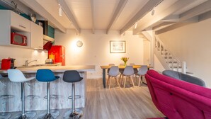 Una cocina moderna con un microondas rojo, una mesa de comedor de madera y sillas, y una escalera que conduce a otro nivel.
