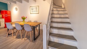 Un comedor con una mesa de madera y cuatro sillas, un refrigerador rojo y una escalera a la derecha.