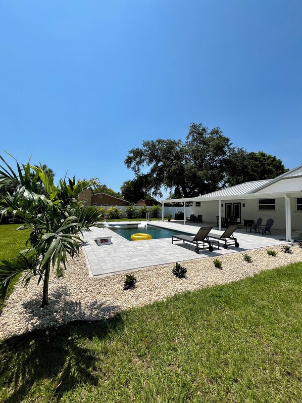 A backyard with a swimming pool, lounge chairs, and a covered patio area. - TOOTSIE’S BEACHSIDE POOL COTTAGE (Seminole)