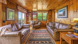 A wooden cabin interior with leather sofas, a rug, and framed pictures on the walls. - Little Greenbriar Lodge: Free Attraction Tickets, Hot Tub, Mtn Views & Adjacent National Park (Sevierville)