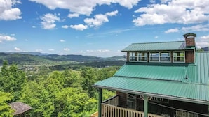 A cabin with a green roof overlooking a forested valley and distant mountains. - Little Greenbriar Lodge: Free Attraction Tickets, Hot Tub, Mtn Views & Adjacent National Park (Sevierville)