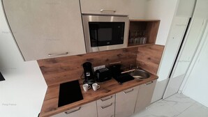 A modern kitchen with a microwave, toaster, and coffee maker on the counter, and a sink with a wooden countertop. - Studio Port Venus Sensation (LE CAP D'AGDE)