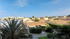 A residential area with terracotta-roofed houses, a marina with boats, and palm trees. - Studio Port Venus Sensation (LE CAP D'AGDE)