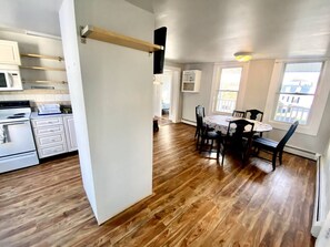 A modern kitchen with white cabinets, a microwave, and a dining area with a wooden table and chairs.