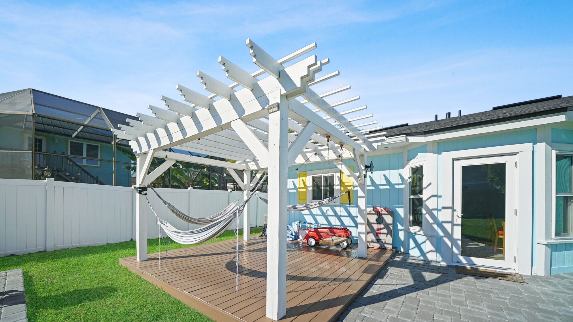 A covered patio area with a hammock, a playhouse, and a small toy car.