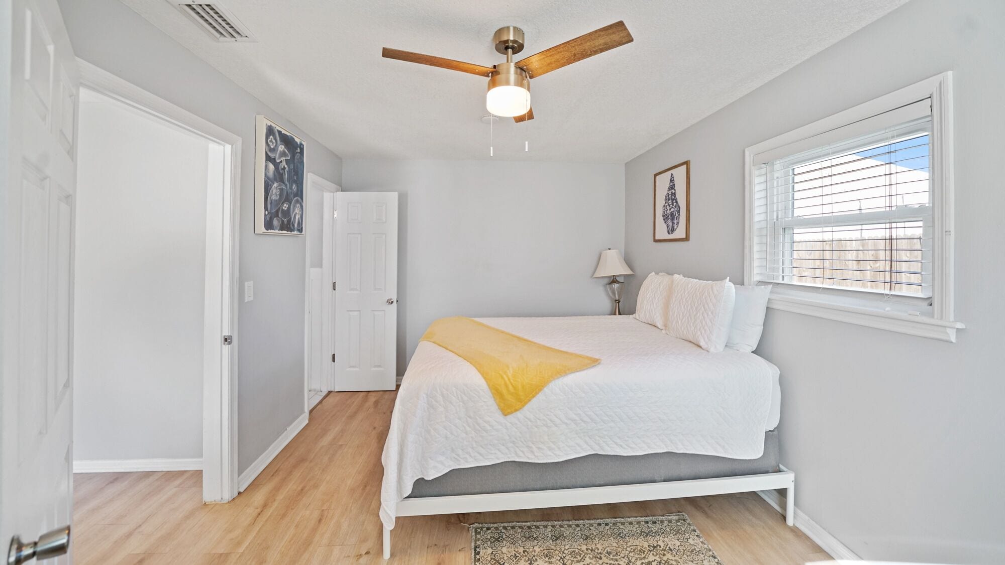 Un dormitorio con cama, ventilador de techo, ventana y puerta.
