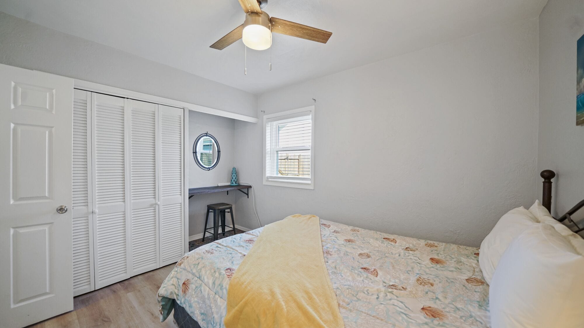 A bedroom with a bed, a ceiling fan, a window, and a wardrobe.