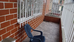 A blue plastic chair on a tiled balcony with a brick wall and metal railing. - Casa Hotel ivanna (Montenegro)