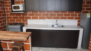 A kitchen with dark cabinets, a microwave, a stove, and a refrigerator. - Casa Hotel ivanna (Montenegro)