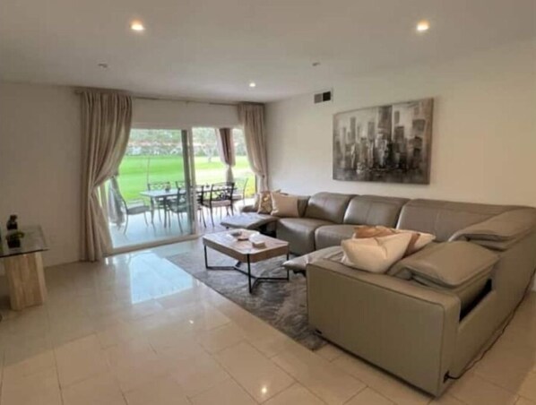Un salon moderne avec un canapé, une table basse et un coin repas avec des chaises.