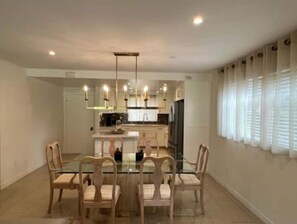 Une cuisine moderne avec des meubles blancs, un îlot central et des luminaires suspendus.