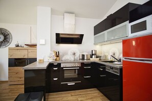 A modern kitchen with black cabinetry, a red refrigerator, and a wooden countertop.