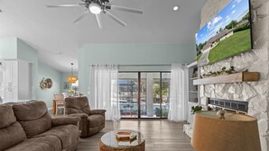 A spacious living room with a large sofa, a coffee table, and a fireplace. There is a sliding glass door leading to a balcony with a pool. - Manatees Coming Waterfront Deep canal.Gulf access.Pool home! Pool table.Sleeps8. (Crystal River)