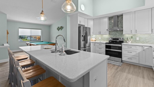 A modern kitchen with a central island, stainless steel appliances, and light-colored cabinetry. - Manatees Coming Waterfront Deep canal.Gulf access.Pool home! Pool table.Sleeps8. (Crystal River)