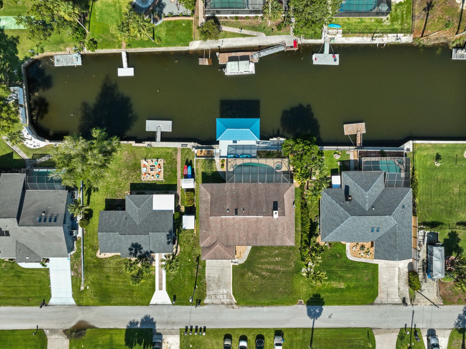 An aerial view of a residential area with houses, a dock, and a small bridge over a water body.