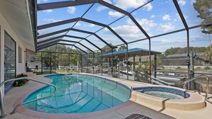 A covered outdoor swimming pool with a glass enclosure, a hot tub, and lounge seating. - Manatees Coming Waterfront Deep canal.Gulf access.Pool home! Pool table.Sleeps8. (Crystal River)