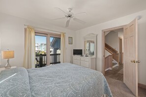 Ein Schlafzimmer mit Bett, Kommode, Fernseher und Deckenventilator.