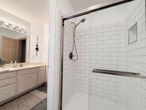 A bathroom with a shower, a sink with a mirror, and a towel rack.