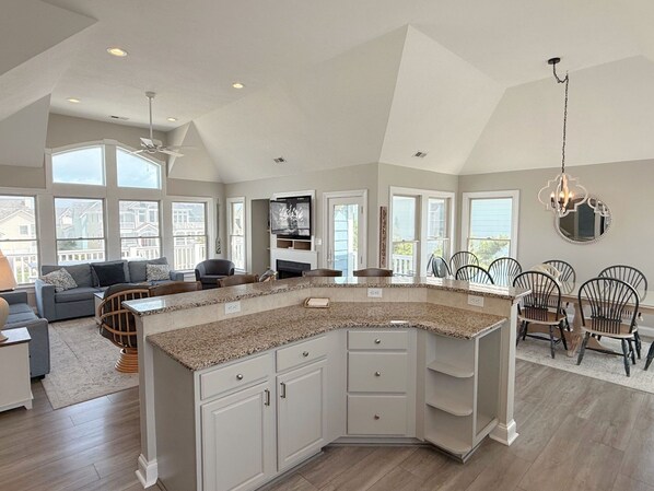A spacious kitchen with a large island, white cabinetry, and a dining area with chairs.