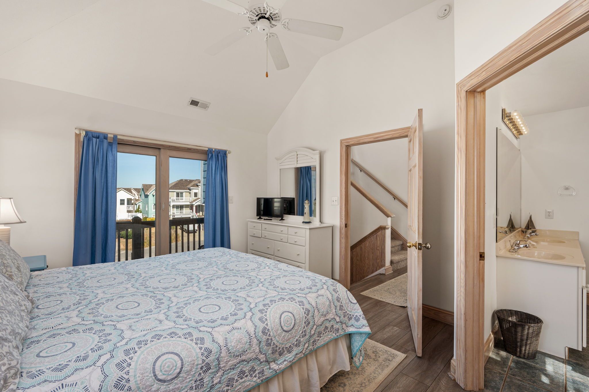 Une chambre à coucher avec un lit, une commode, un téléviseur et une vue sur l’extérieur.