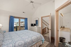 A bedroom with a bed, a dresser, a television, and a view of the outside.