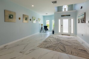Um corredor amplo com paredes azul-claras, piso de mármore e um tapete decorativo grande.